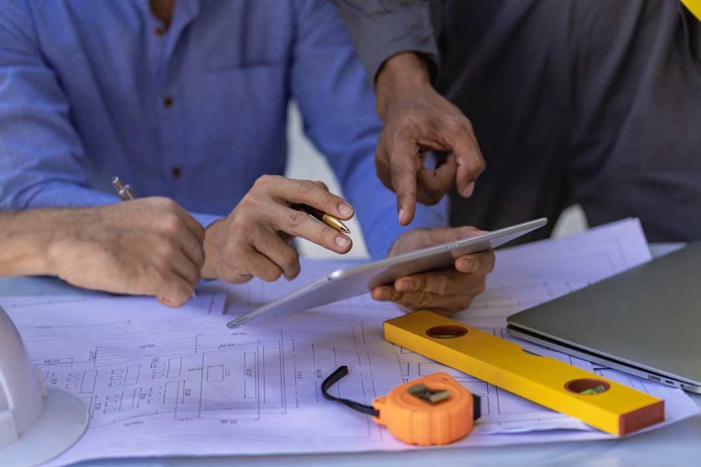 Engineer Team Meeting And Talking Using Laptop Blueprints And Pa